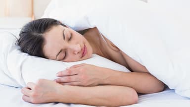 Ein Frau liegt im Bett und schläft - Tipps für das Schlafen, trotz Hitze gibt es hier.