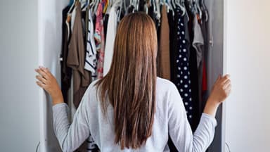 Junge Frau räumt ihren Kleiderschrank auf