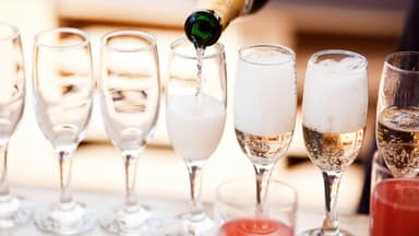 Eingießen von Sekt aus Sektflasche in mehrere Sektgläser