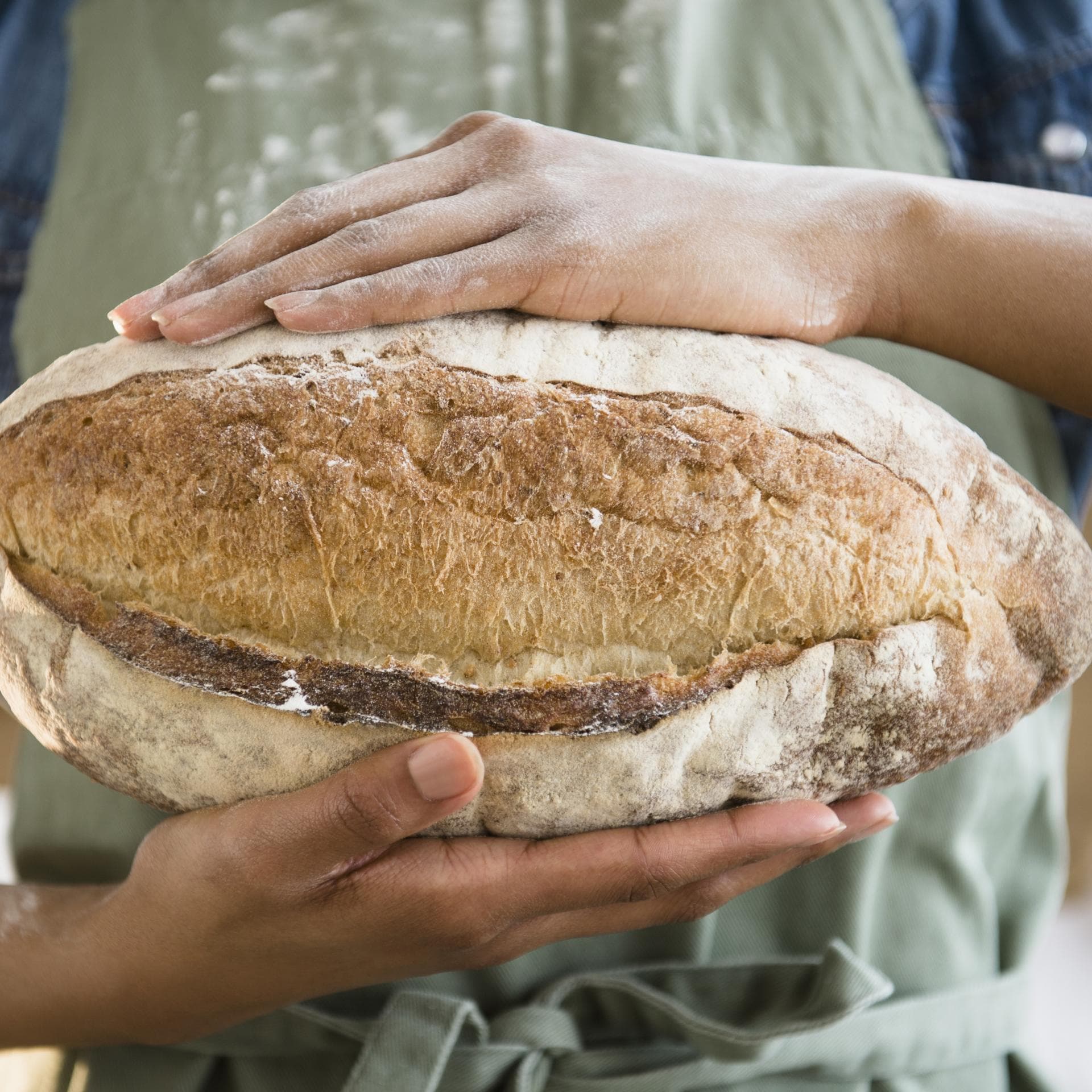 Frau hält selbstgebackenes Roggenbrot in den Händen - Das Backrezept gibt es hier