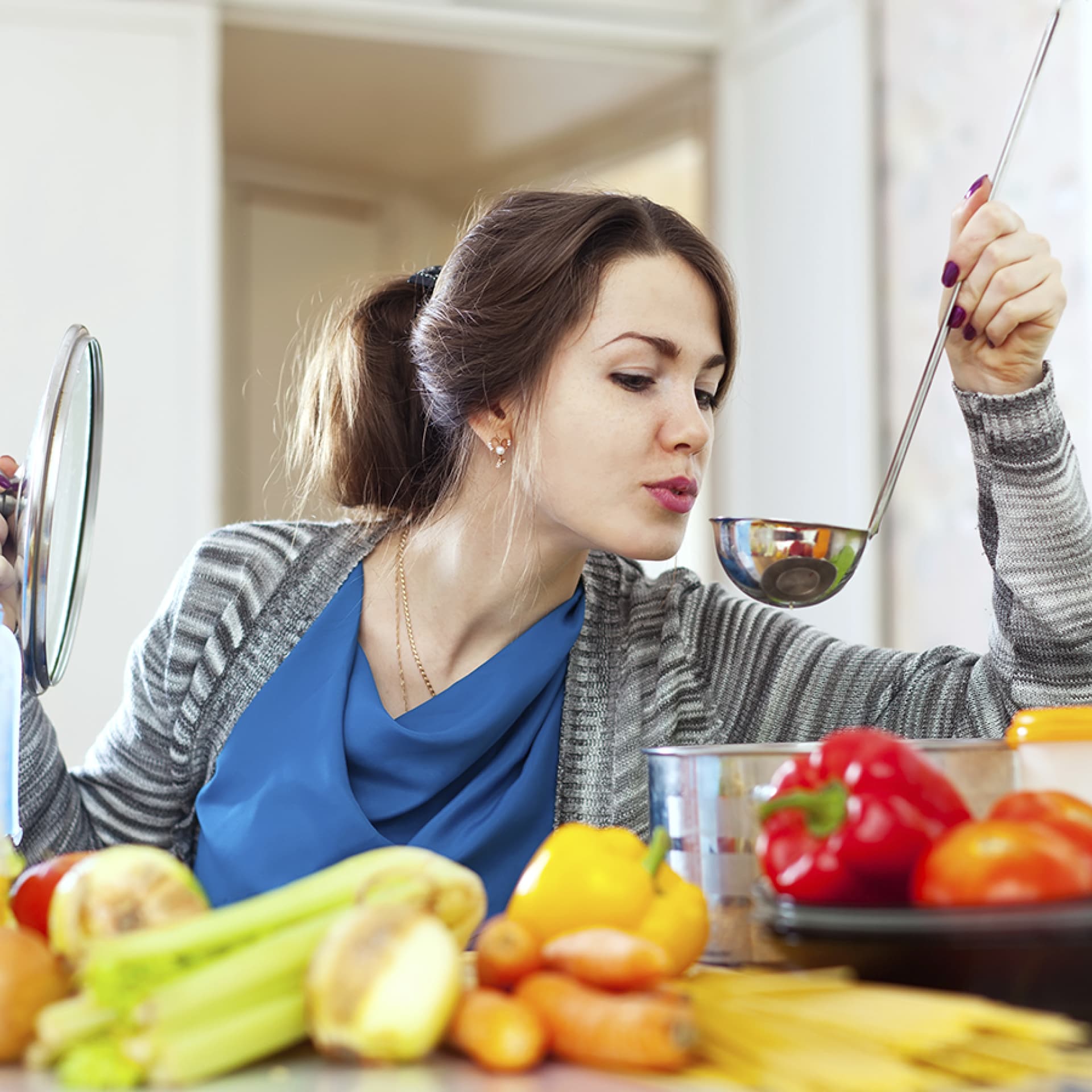 Frau kocht und probiert von einer Kelle - So kochen Sie kalorienarm und gesund
