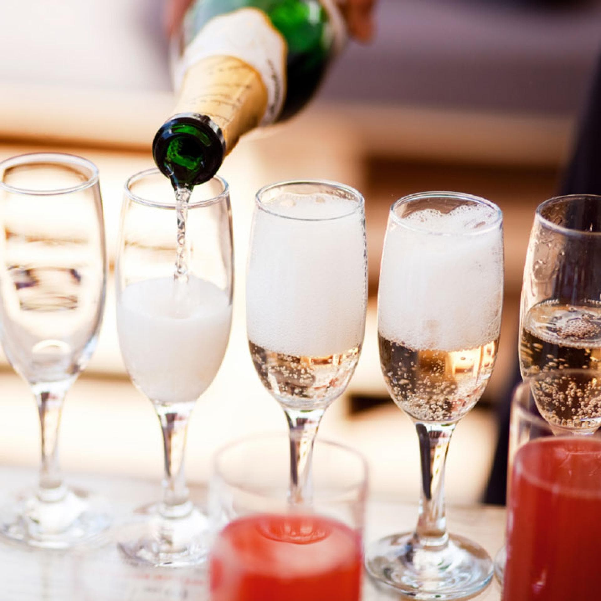 Eingießen von Sekt aus Sektflasche in mehrere Sektgläser