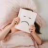 Frau liegt im Bett und schmollt