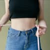 schlanke Frau misst Bauch mit Maßband
