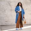 Frau in weiter Hose und blauem Mantel