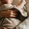 Frau hält ein Baby, das in eine Decke gehüllt ist.