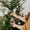 Frau schmückt Weihnachtsbaum mit Christbaumschmuck 