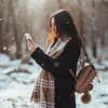 Frau hält Smartphone im Winter