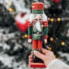 Frau hält einen Nussknacker vor winterlichen Hintergrund.