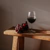 Ein Glas Rotwein und Trauben auf einer Holzbank.