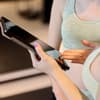Frau zeigt kostenlose Trainingspläne auf dem Tablet