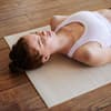 Frau liegt mit dem Rücken auf einer Yogamatte