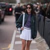 Frau mit Sonnenbrille, Collegejacke und Tennisrock
