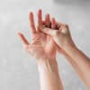Die rechte Hand fasst an den linken Mittelfinger