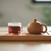 Yogi Tee in einem Glas mit Teekanne daneben