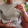 Frau wirft Brausetablette in ein Glas Wasser