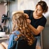 Frau macht einer anderen Frau eine festliche Frisur mit Locken