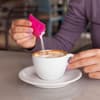Frau schüttet Zucker oder Süßstoff in ihren Kaffee