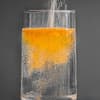 Glas Wasser mit orangefarbener Brause