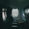 Frau sitzt im Flugzeug am Fenster.