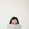 Frau versteckt sich hinter einem Buch