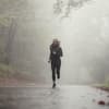 Frau beim Joggen bei Regen im Wald.