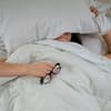 Frau liegt im Bett mit Kissen auf dem Kopf
