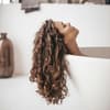 Frau mit lockigem Haar in der Badewanne
