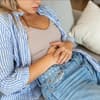 Frau liegt auf dem Sofa und hält ihre Hände auf dem Bauch