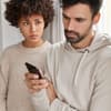 Frau schaut Partner aufs Handy
