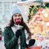 Frau isst einen Bratapfel auf dem Weihnachtsmarkt