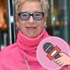 Regisseurin, Produzentin, Autorin Doris Dörrie lächelt aufgeweckt in die Kamera. Sie trägt einen knallig pinken Pullover und eine Brille mit blau getönten Gläsern.