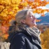 Eine Frau steht unter einem Baum im Herbst