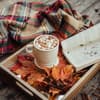 Ein heißes Getränk, ein Buch und eine Decke sorgen für eine perfekte Auszeit im Herbst