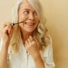 Frau verwendet Anti-Aging-Mascara mit Hyaluron