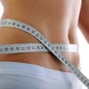 Frau mit Maßband um den Bauch