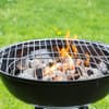 Schwarzer Holzkohlegrill mit glühenden Kohlen und Flamme