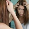 Frau prüft graue Haare – graue Haare durch Stress