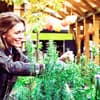 Eine Frau arbeitet in ihrem Garten - welche Geräte dabei nicht fehlen sollten, erfahren Sie hier 
