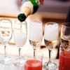 Eingießen von Sekt aus Sektflasche in mehrere Sektgläser