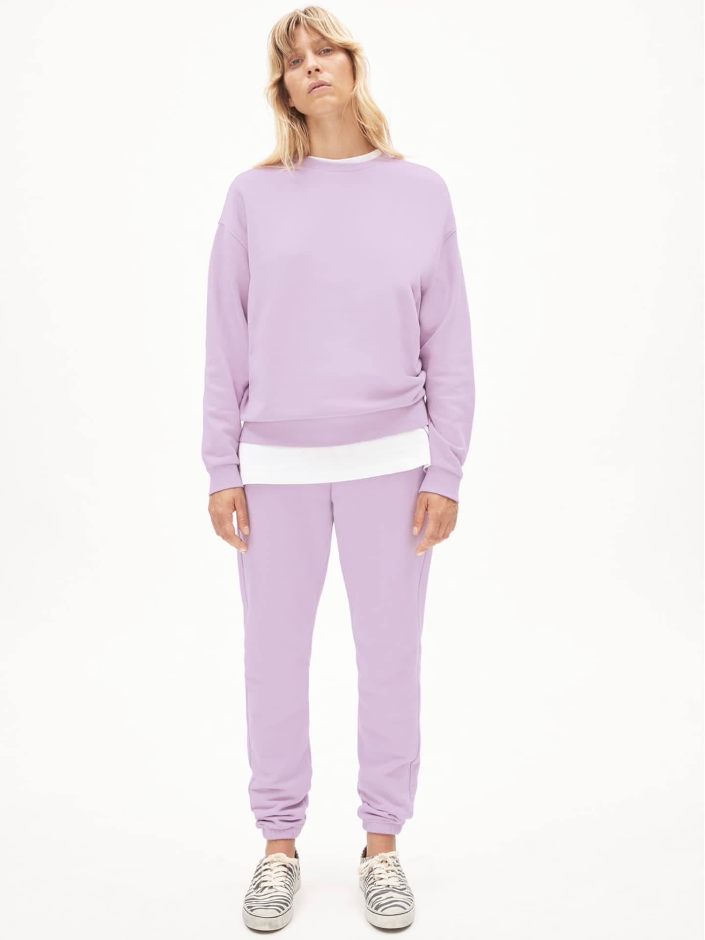 Frau trägt Jogginganzug in Bonbonfarbe von Armedangels.