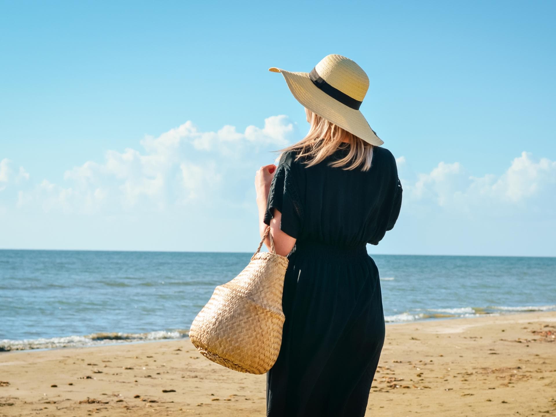 Frau in schwarzem Kleid am Strand