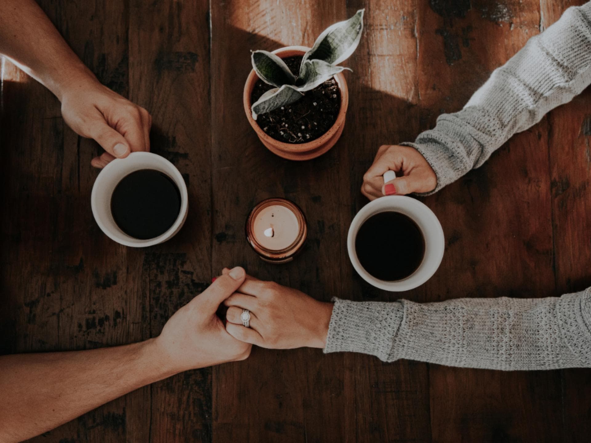 Paar hält Händchen beim Kaffeetrinken