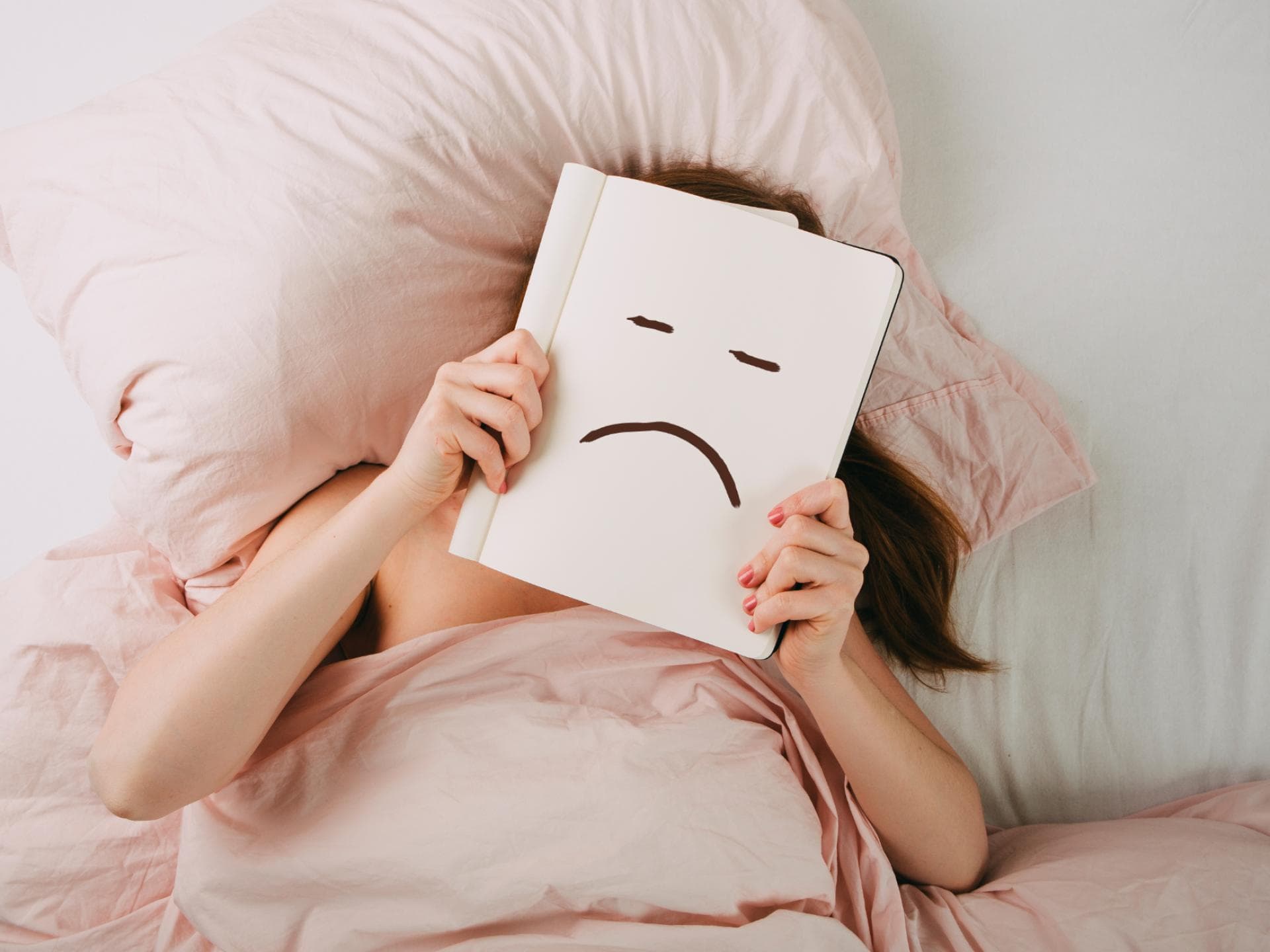Frau liegt im Bett und schmollt