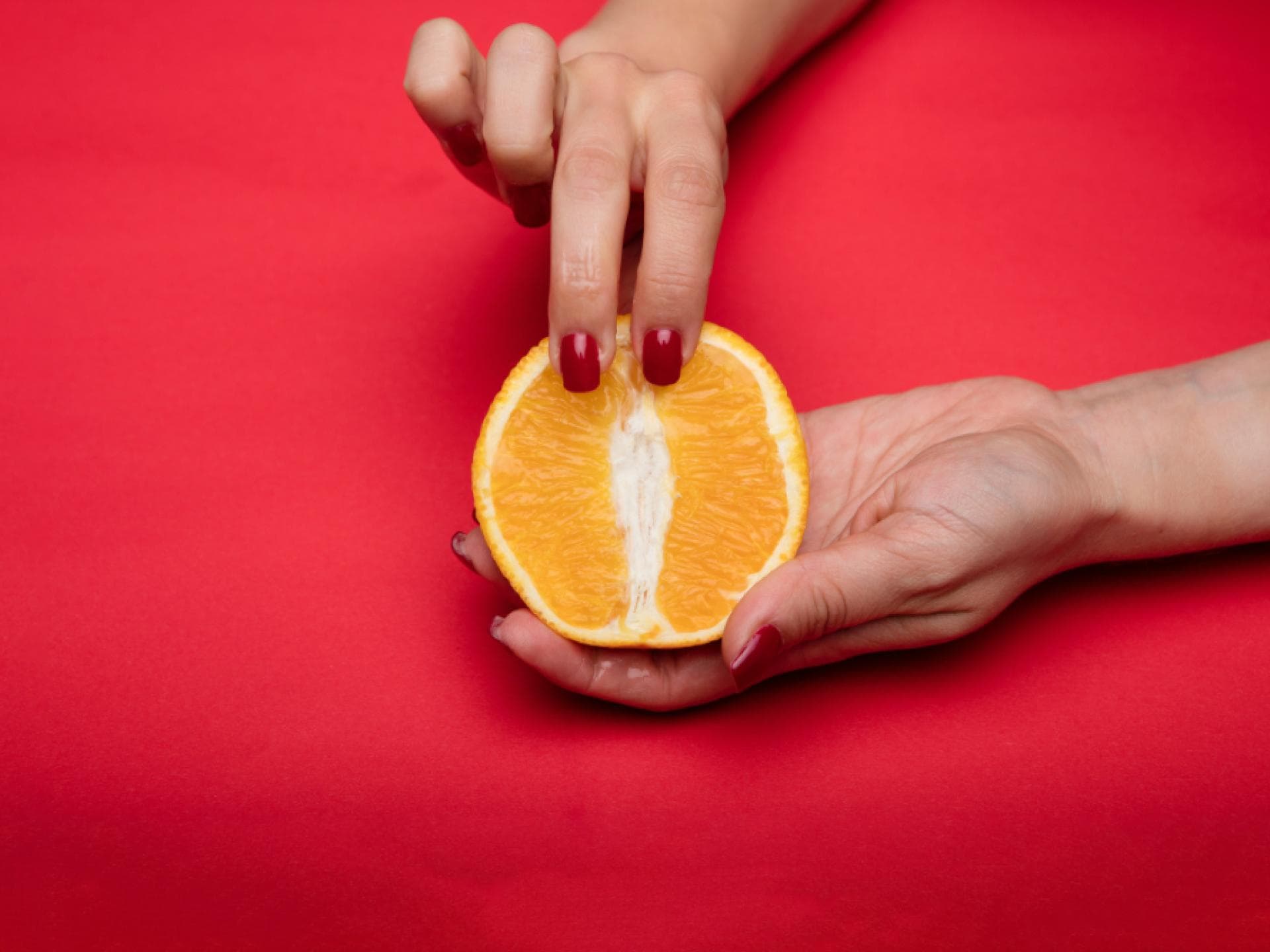 Frau hält aufgeschnittene Orange