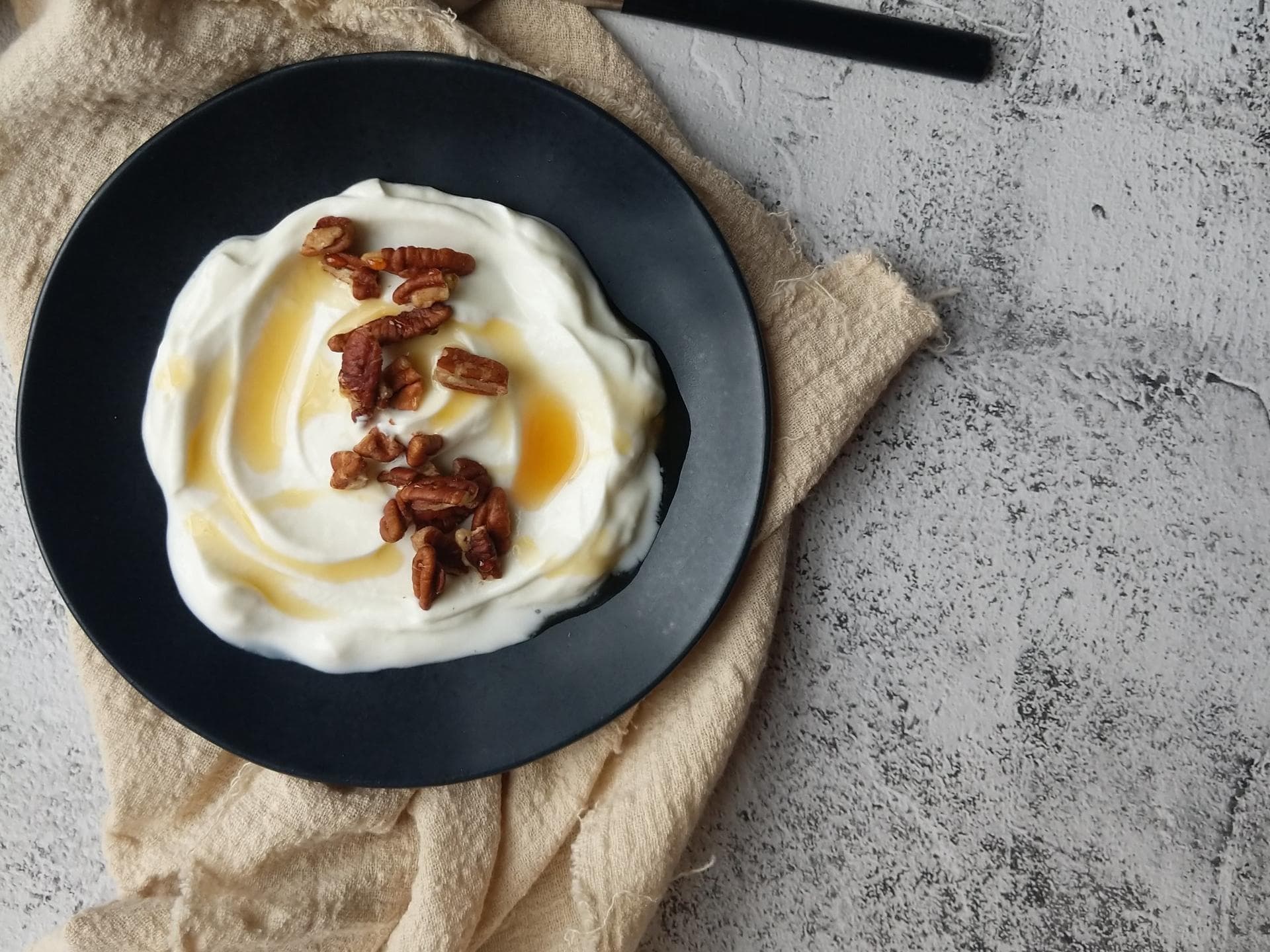 Skyr mit Nüssen in einer schwarzen Schüssel.