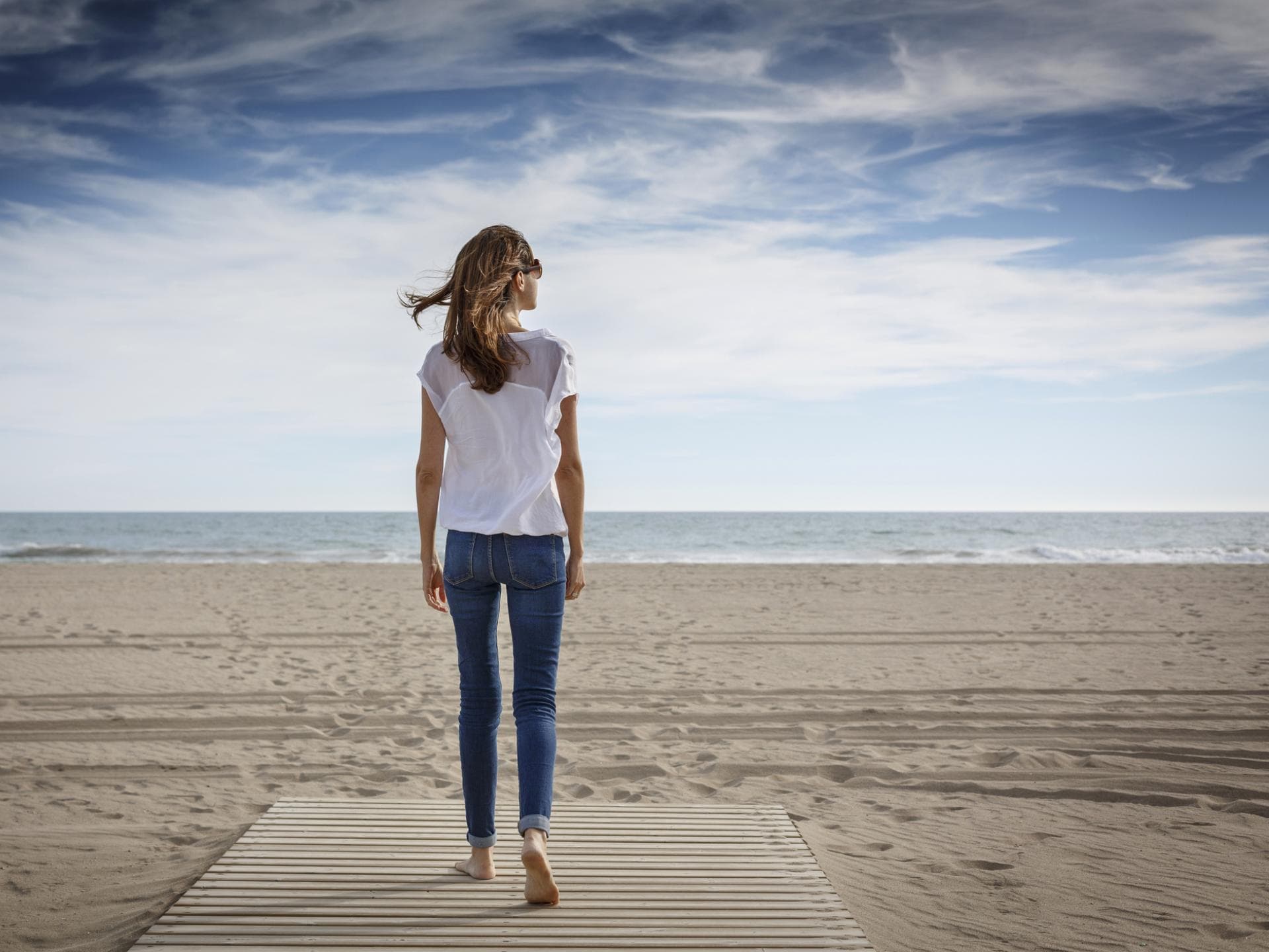 Frau beim Rückwärtsgehen am Meer