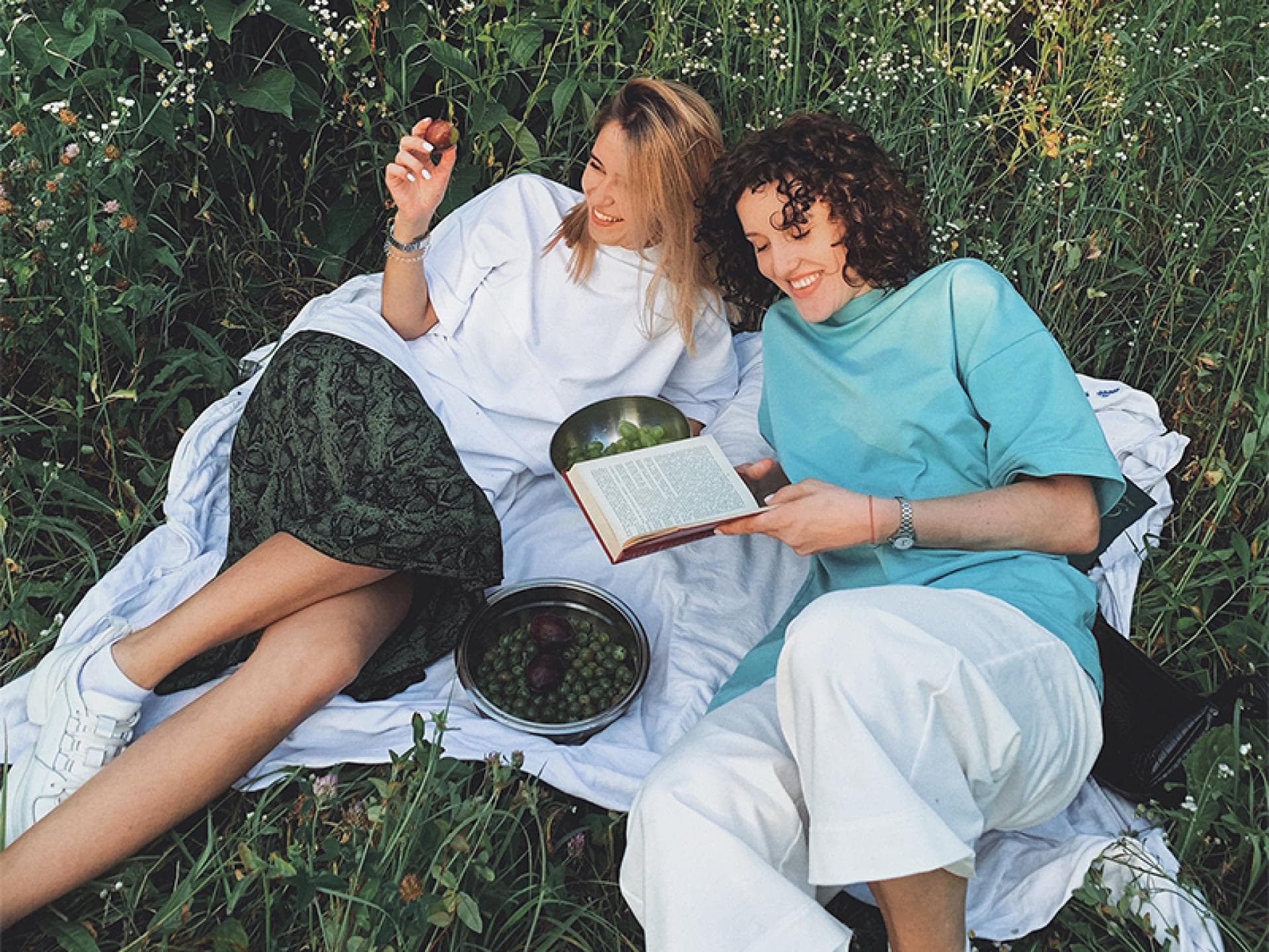 Zwei Frauen auf Picknickdecke beim Lesen