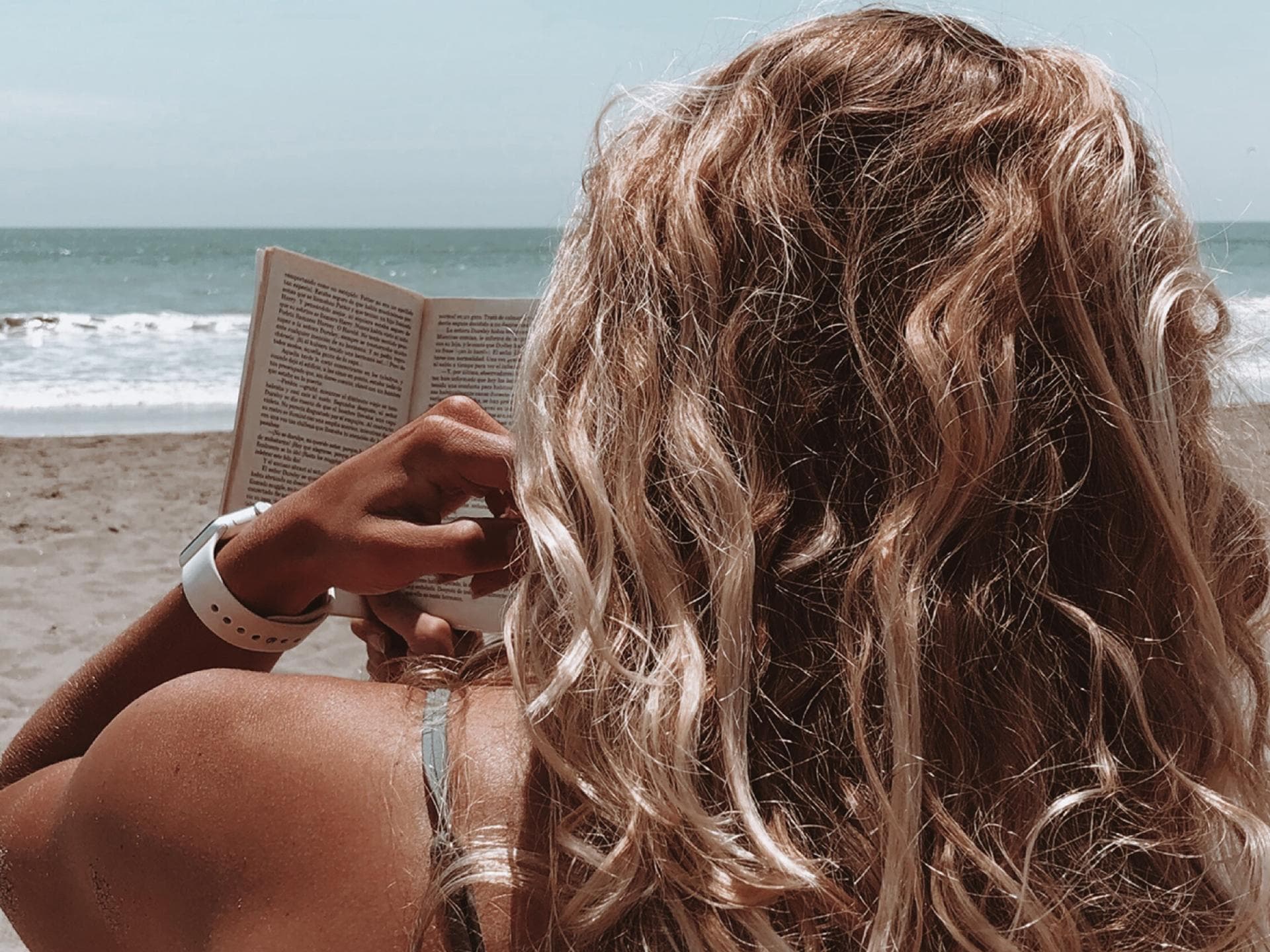 Frau liest am Strand ein Buch