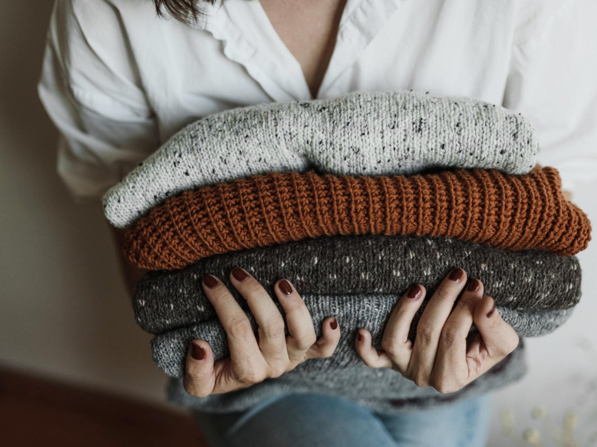Frau mit einem Stapel Wollpullover